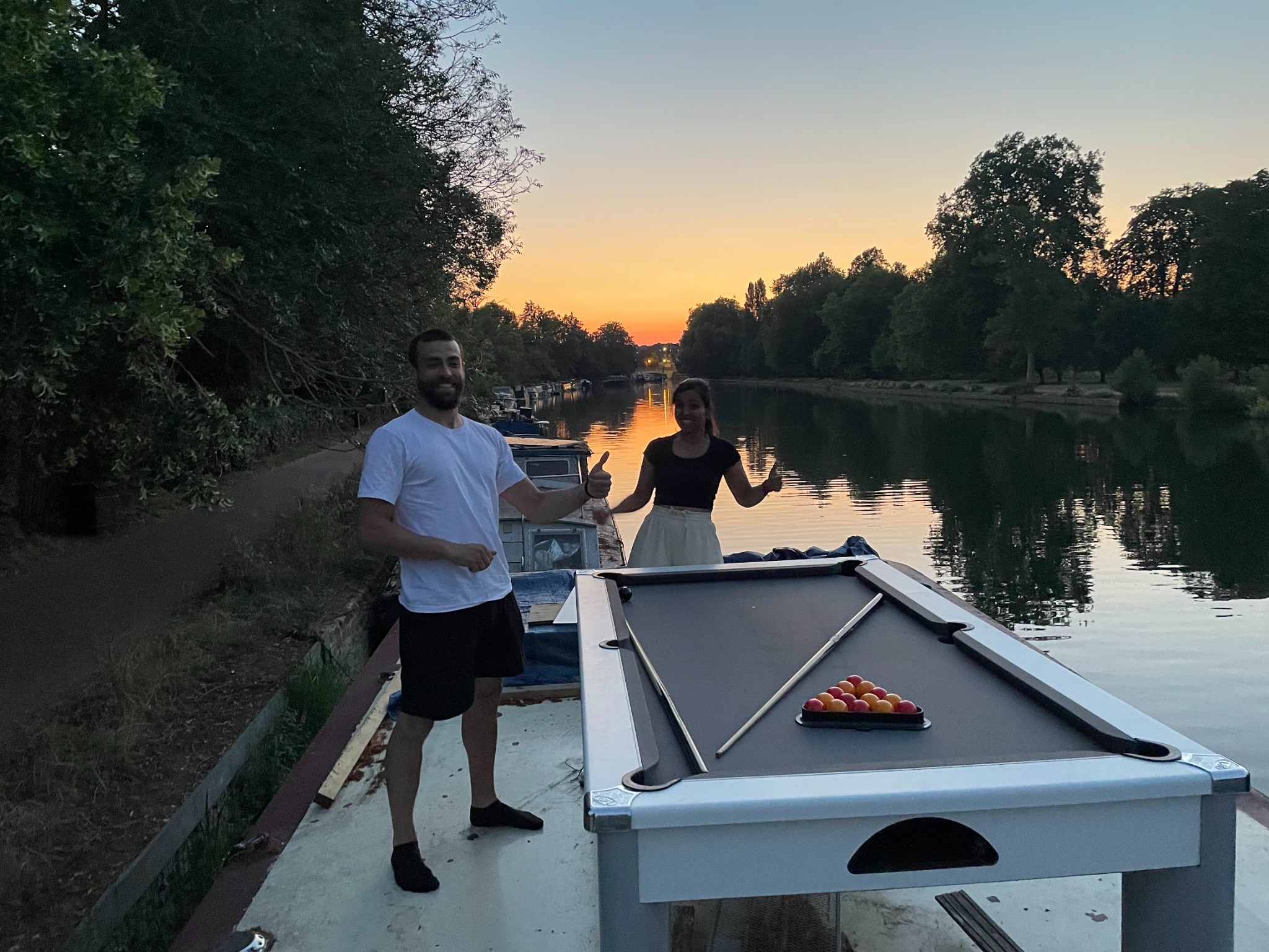 CANN lab members on a boat at sunset with an outdoor pool table.